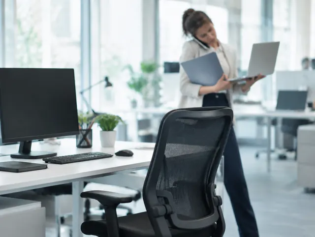 Leerer Arbeitsplatz, während eine Kollegin die zusätzliche Arbeit auffangen muss